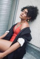 Artist sitting on the floor with red dress and black jacket